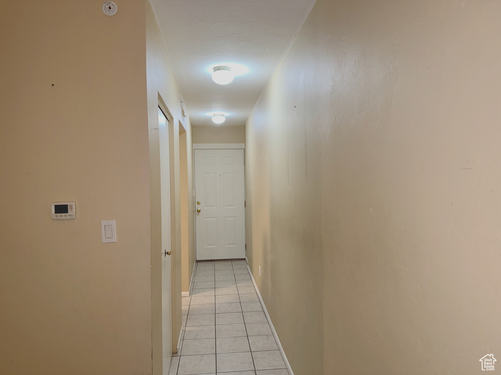 Corridor featuring light tile patterned floors and baseboards