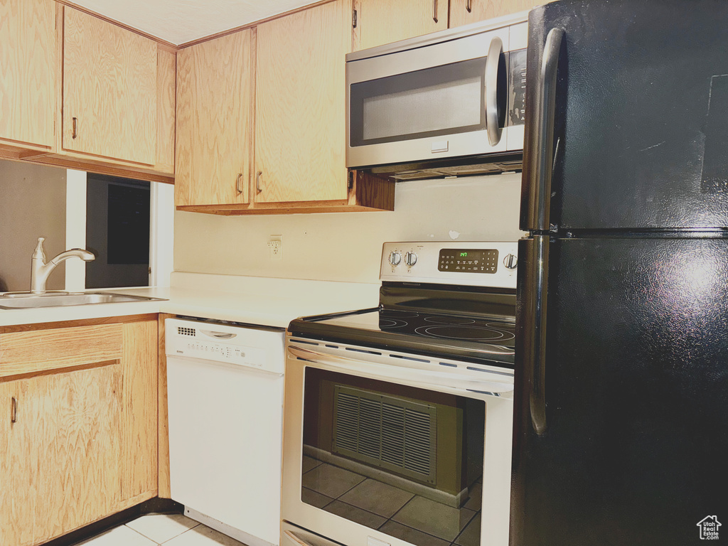 Kitchen featuring stainless steel appliances, a sink, light tile patterned floors, light countertops, and light brown cabinets