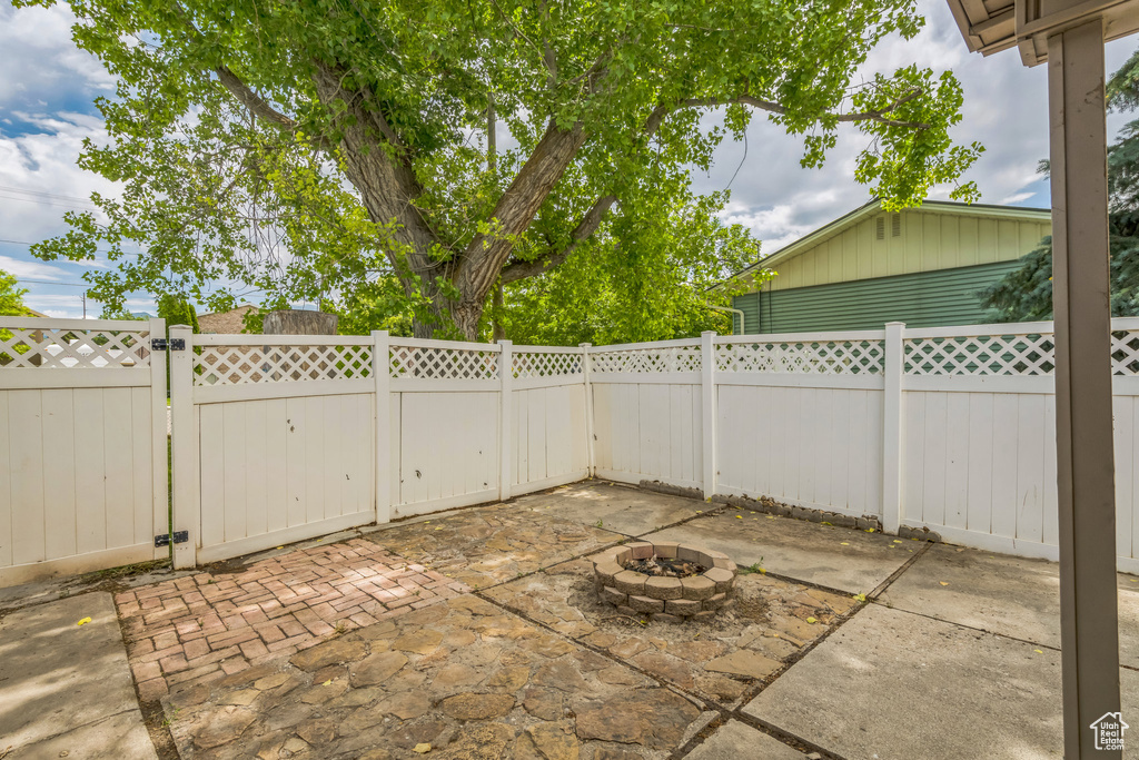 Fenced backyard with a gate, a patio area, and an outdoor fire pit
