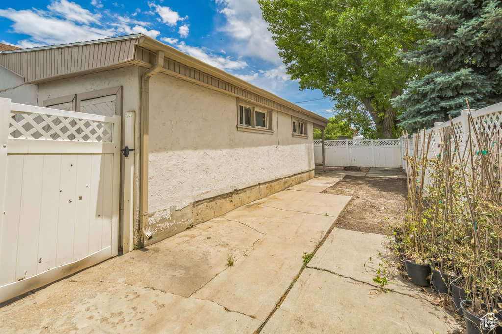View of side of property with a fenced backyard, stucco siding, a gate, and a patio