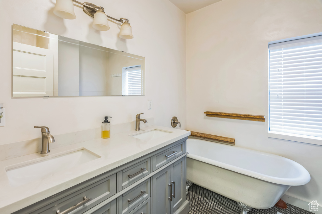 Full bath featuring a freestanding tub, double vanity, and tile patterned floors