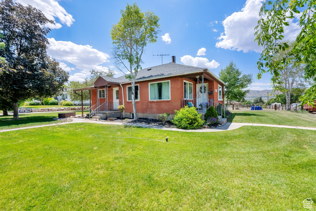 View of front of home featuring brick siding, a front yard, and roof with shingles