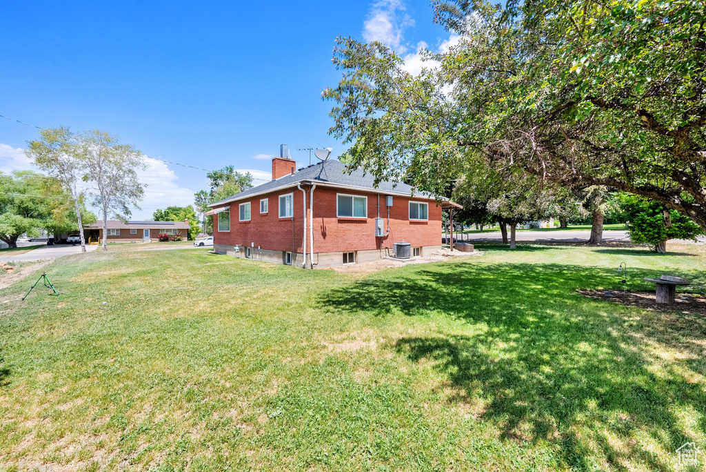 View of home's exterior with a chimney, a lawn, and brick siding