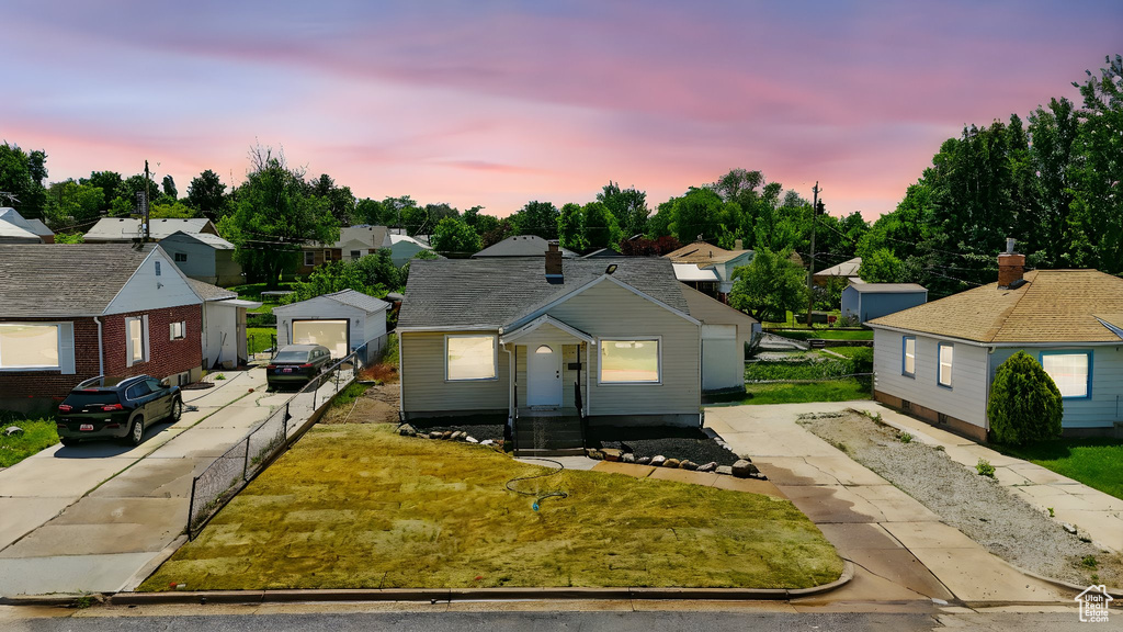 Bungalow-style home featuring a residential view, concrete driveway, and a yard