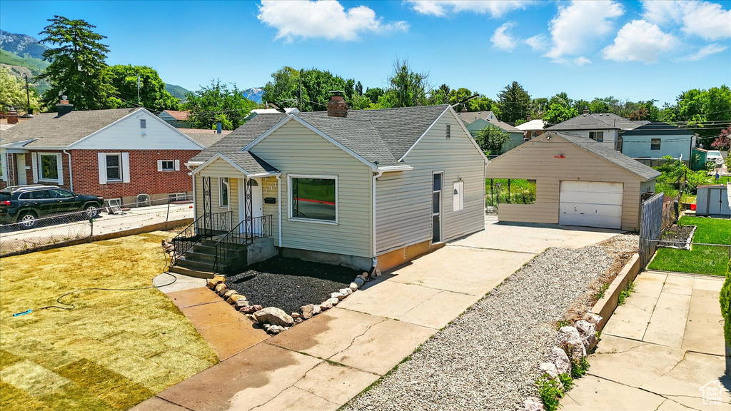View of front of home with an outdoor structure, a garage, a chimney, concrete driveway, and a shingled roof