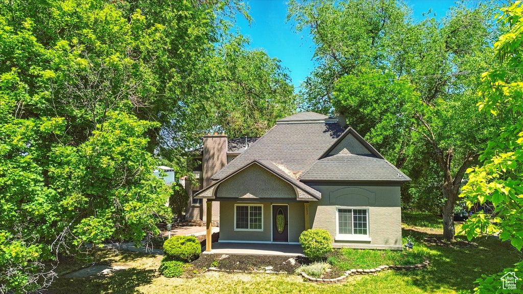 View of front of property featuring a chimney, roof with shingles, and covered porch
