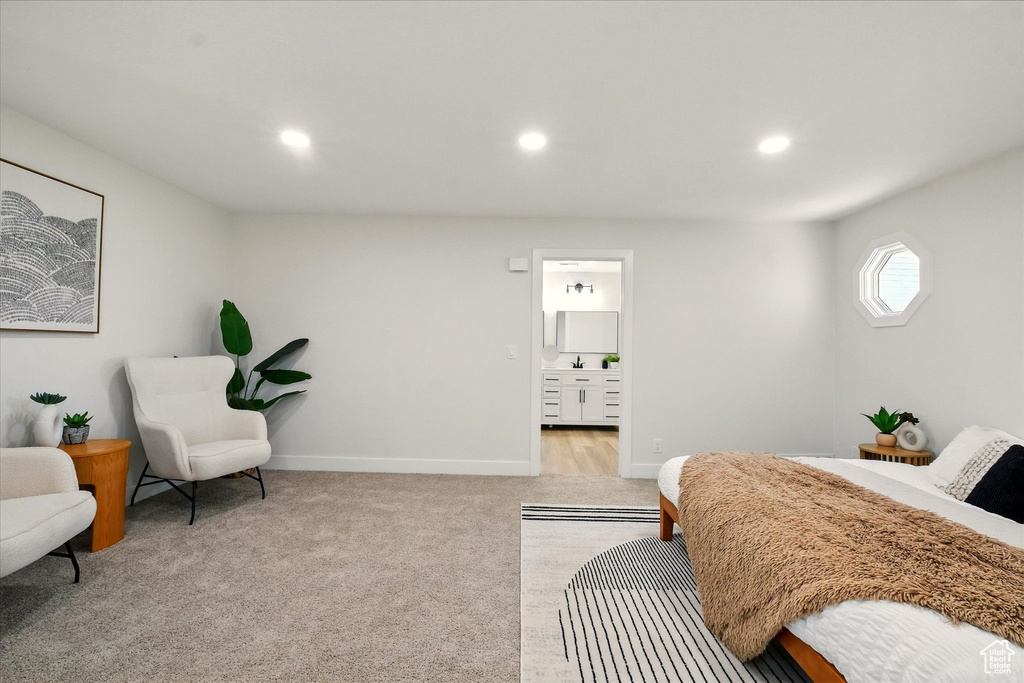 Bedroom with light colored carpet, recessed lighting, and connected bathroom