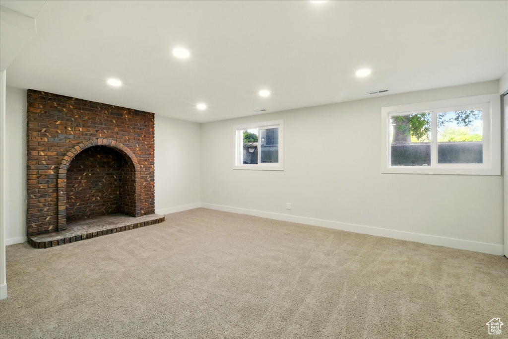 Unfurnished living room featuring light colored carpet, recessed lighting, plenty of natural light, and a brick fireplace