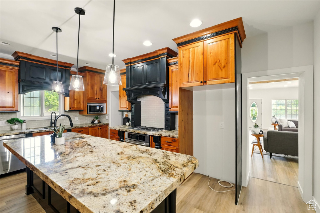 Kitchen featuring appliances with stainless steel finishes, plenty of natural light, light stone countertops, backsplash, and recessed lighting