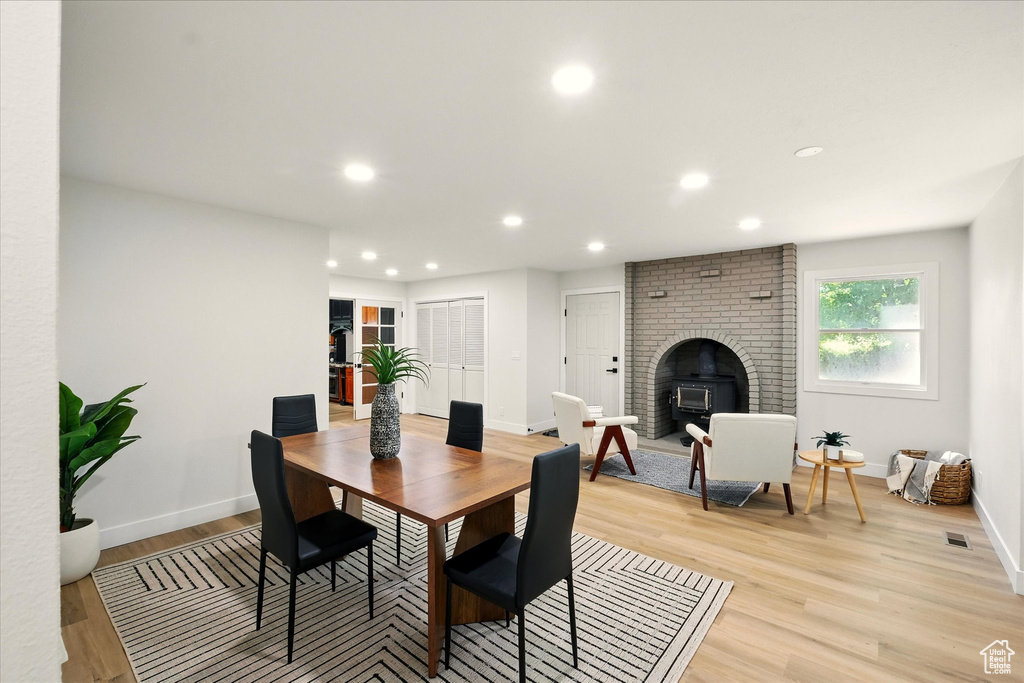 Dining space featuring light wood-style flooring, recessed lighting, and a brick fireplace
