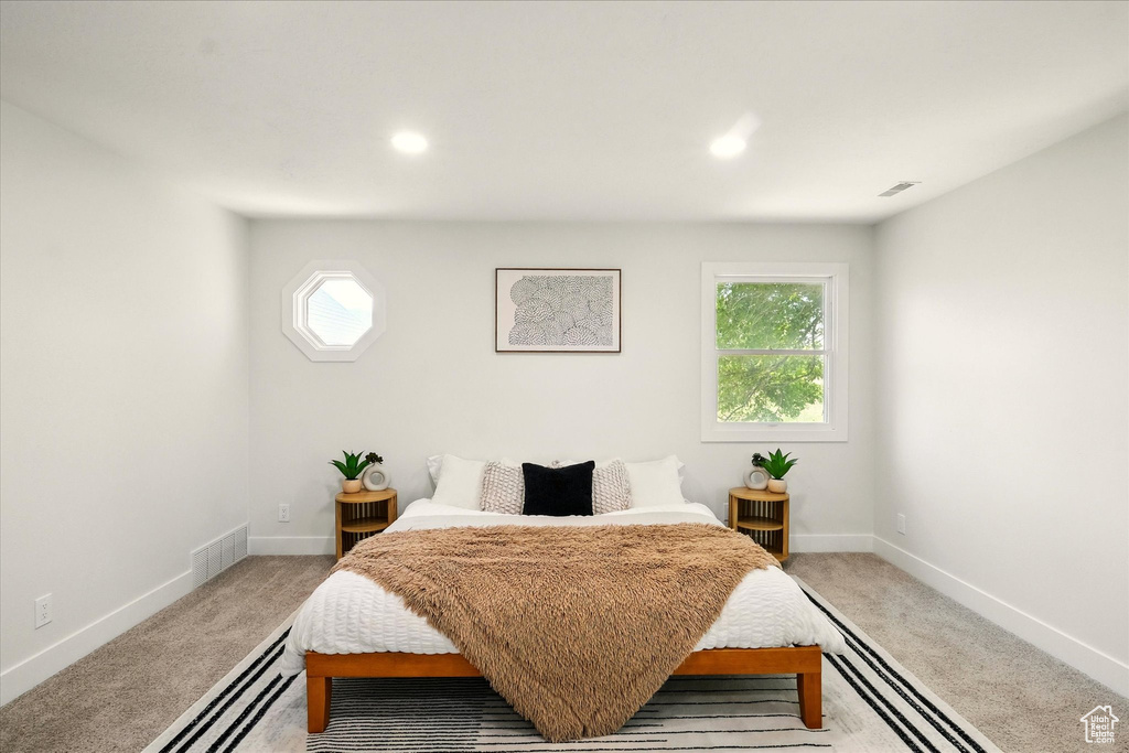 Bedroom featuring light carpet, multiple windows, and recessed lighting