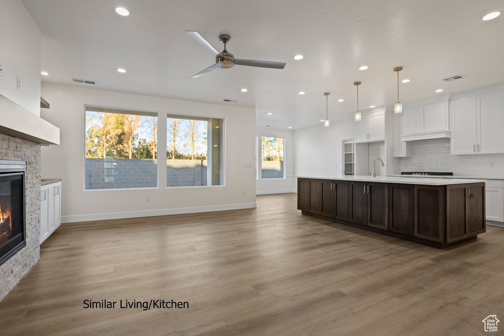 Kitchen with a stone fireplace, light countertops, a ceiling fan, recessed lighting, and black stovetop