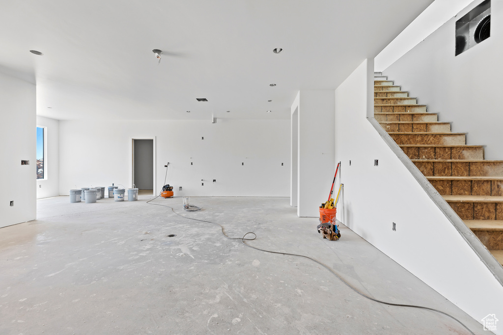 Unfurnished living room with stairs and concrete flooring