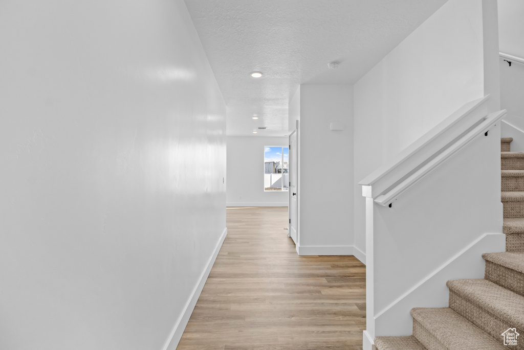 Corridor featuring stairway, light wood-style flooring, recessed lighting, and a textured ceiling