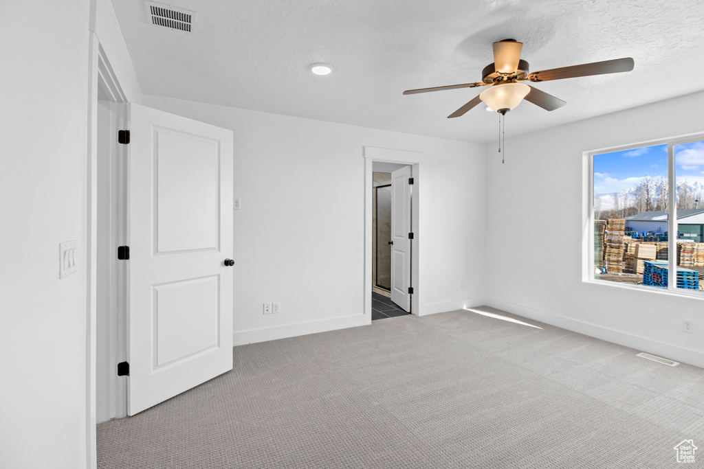 Unfurnished bedroom with carpet, a ceiling fan, and ensuite bath