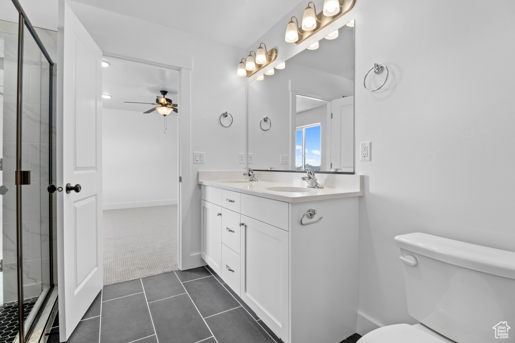 Full bathroom featuring a ceiling fan, double vanity, a shower stall, and tile patterned flooring