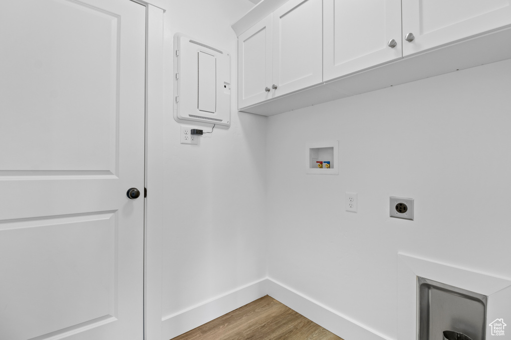 Washroom with electric panel, electric dryer hookup, cabinet space, wood finished floors, and hookup for a washing machine