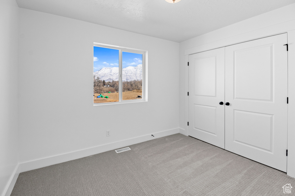 Unfurnished bedroom featuring light colored carpet and a closet