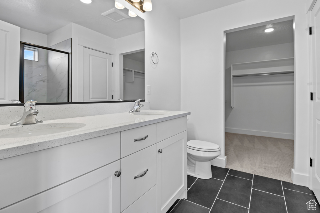 Bathroom featuring a walk in closet, double vanity, a stall shower, and tile patterned flooring