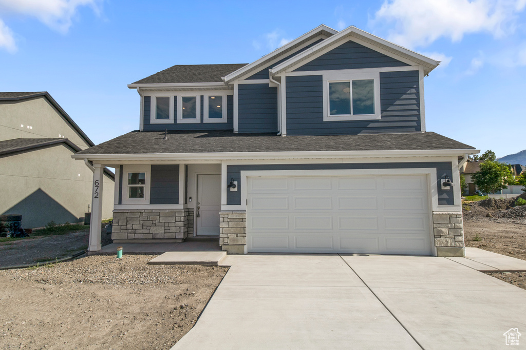 Craftsman-style home featuring stone siding, driveway, a garage, a porch, and a shingled roof