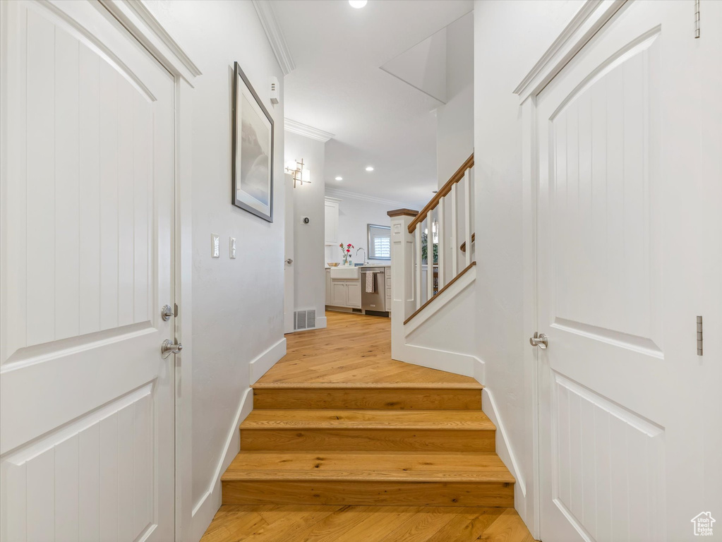 Staircase with ornamental molding, wood finished floors, recessed lighting, and baseboards