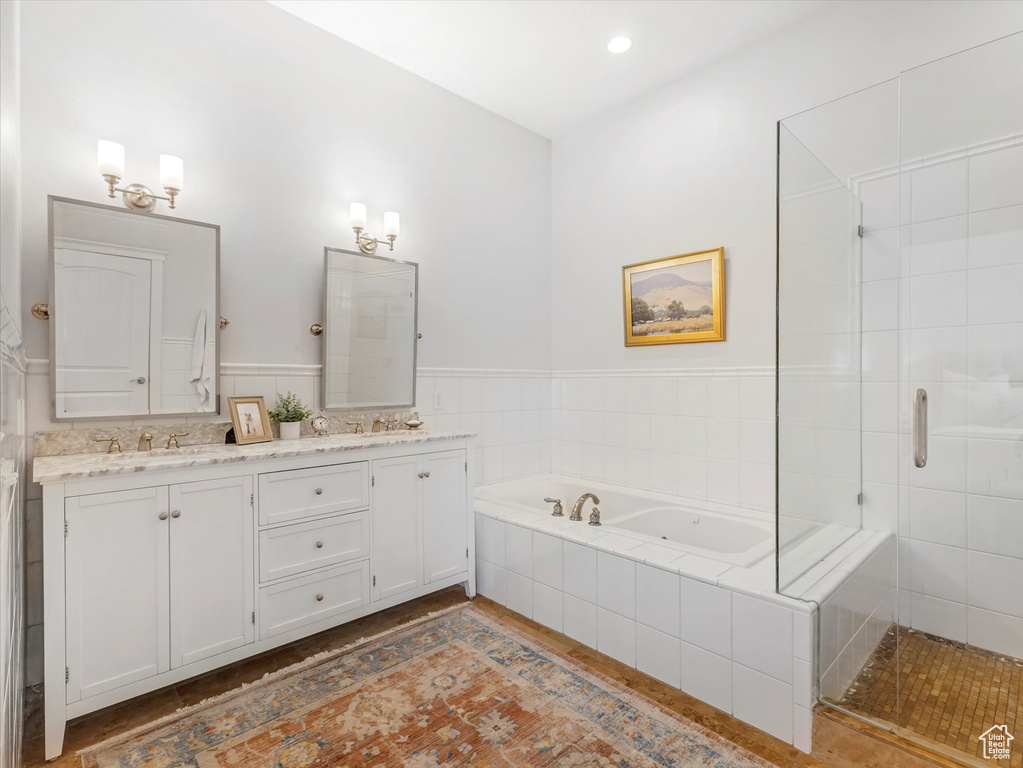 Full bathroom with double vanity, a bath, a shower stall, and wood finished floors