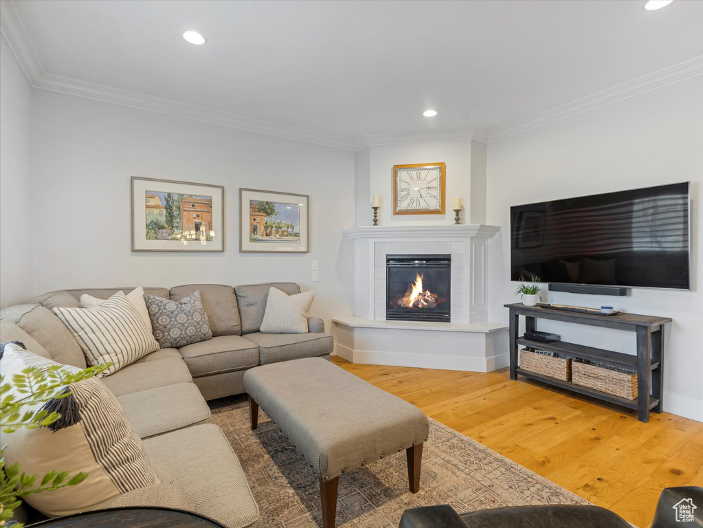 Living area featuring ornamental molding, wood finished floors, recessed lighting, a tiled fireplace, and baseboards