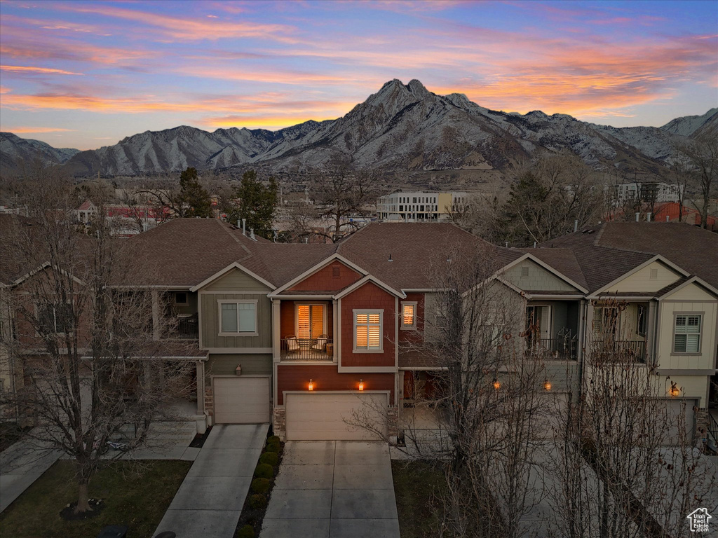 View of front of house featuring a garage, a mountain view, driveway, and stone siding
