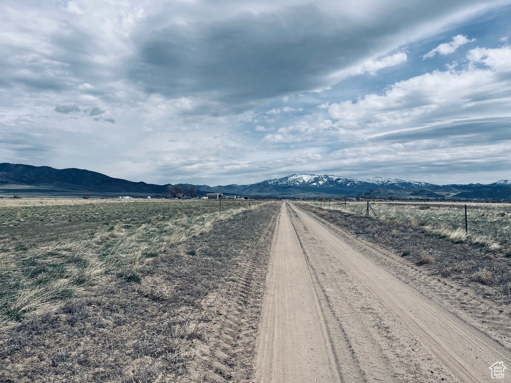 View of dirt / gravel road featuring a mountain view and a view of countryside