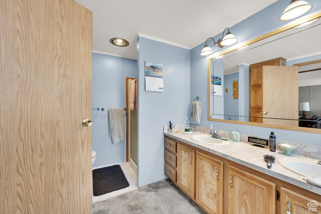 Bathroom with double vanity, ornamental molding, and a shower with door