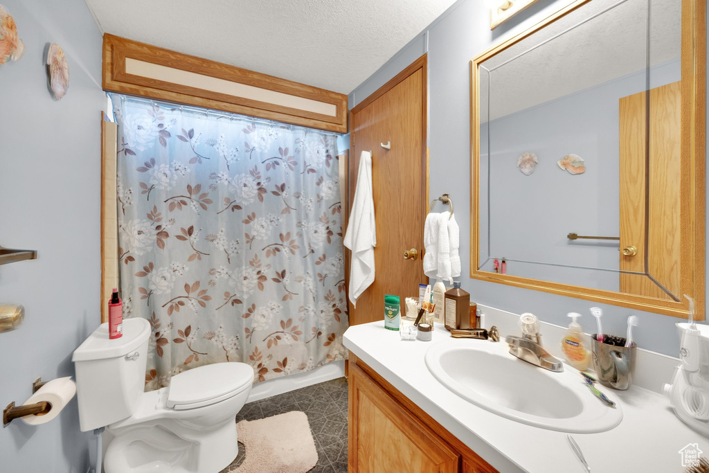 Full bath with vanity, tile patterned flooring, and a textured ceiling