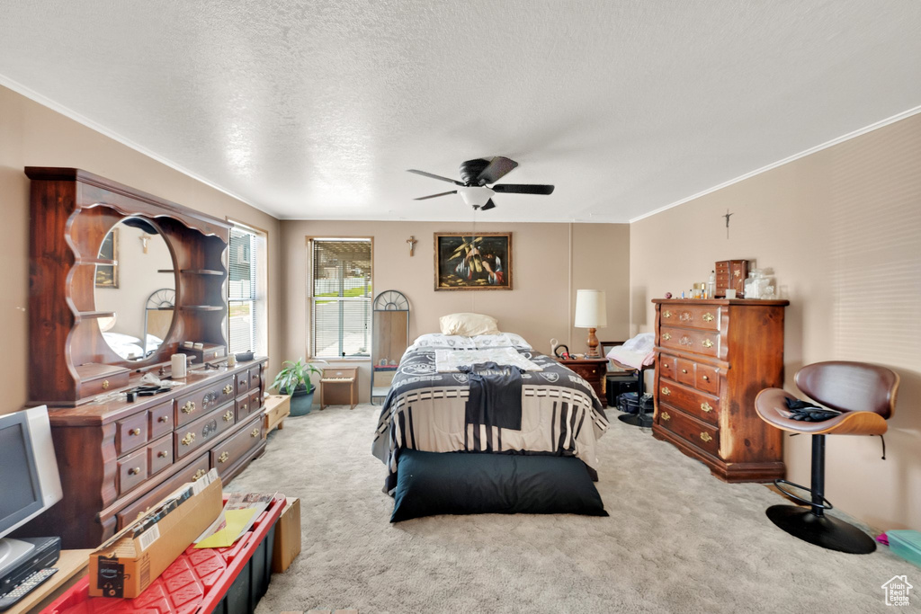 Carpeted bedroom with ornamental molding, a textured ceiling, and a ceiling fan