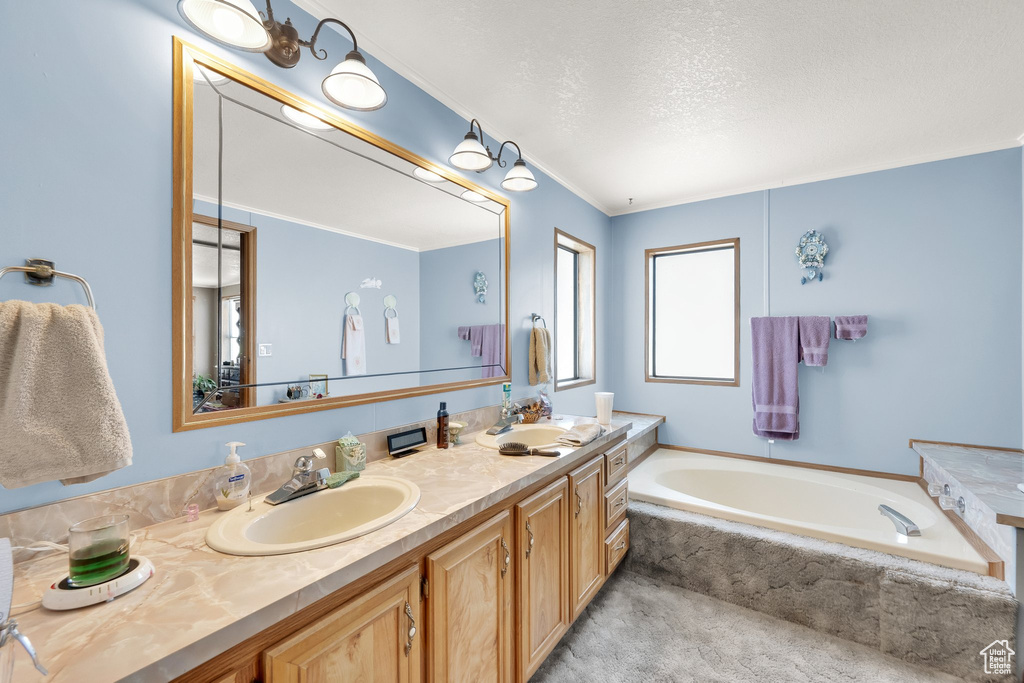 Full bathroom with double vanity, a bath, a textured ceiling, and ornamental molding