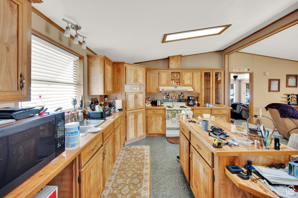 Kitchen with white electric stove, lofted ceiling, butcher block counters, and under cabinet range hood
