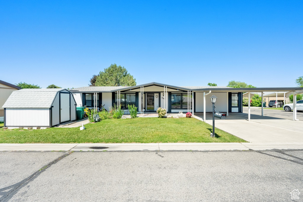 View of front facade with a storage unit, a front lawn, and driveway