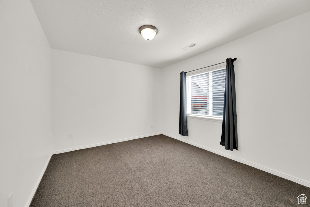 Unfurnished room featuring dark carpet and baseboards
