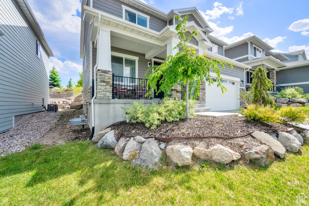 View of front of home featuring covered porch, stone siding, and an attached garage