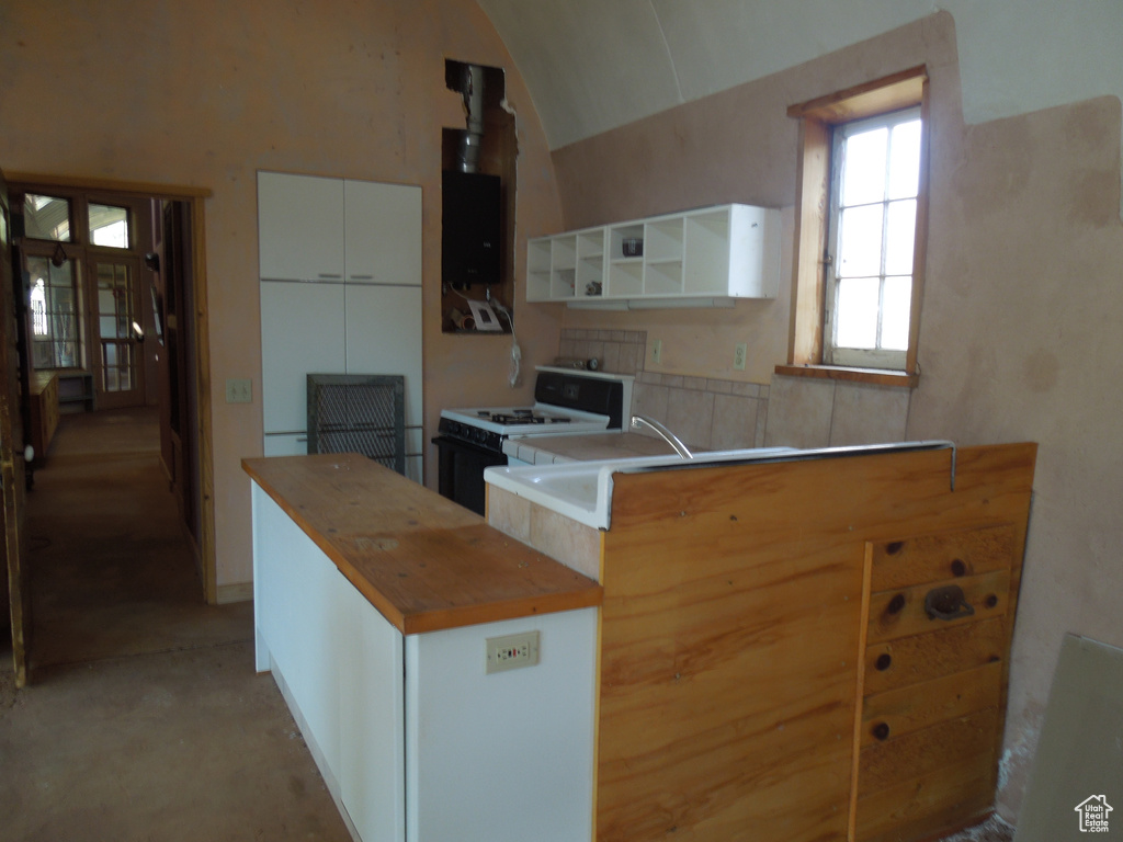 Kitchen with white range with gas cooktop, wood counters, open shelves, light colored carpet, and white cabinetry