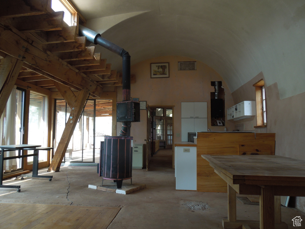 Miscellaneous room featuring a wood stove, healthy amount of natural light, and lofted ceiling