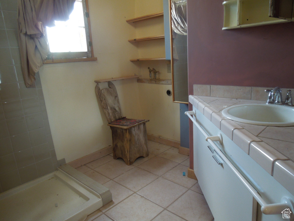 Full bath featuring vanity, tiled shower, and tile patterned floors