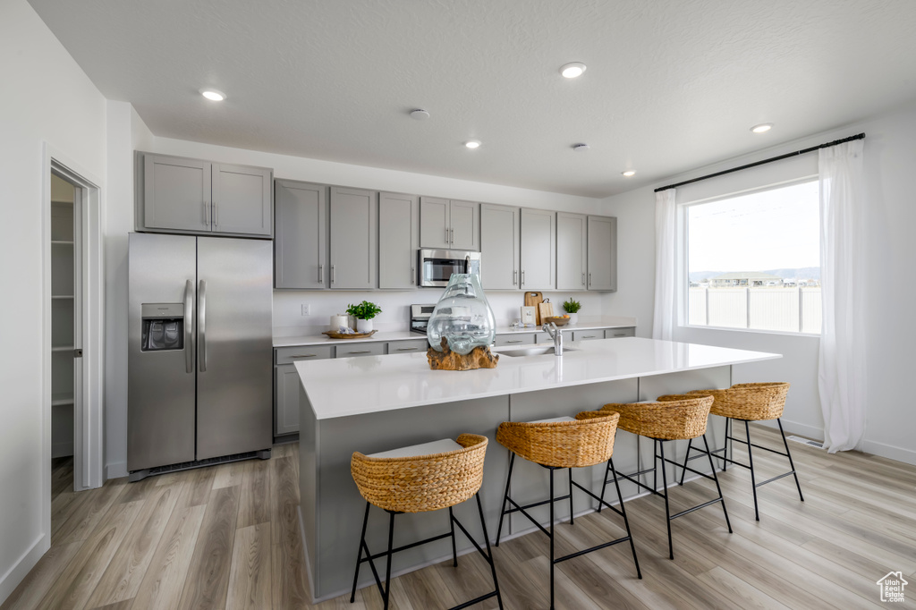 Kitchen with appliances with stainless steel finishes, gray cabinetry, light wood-type flooring, and recessed lighting