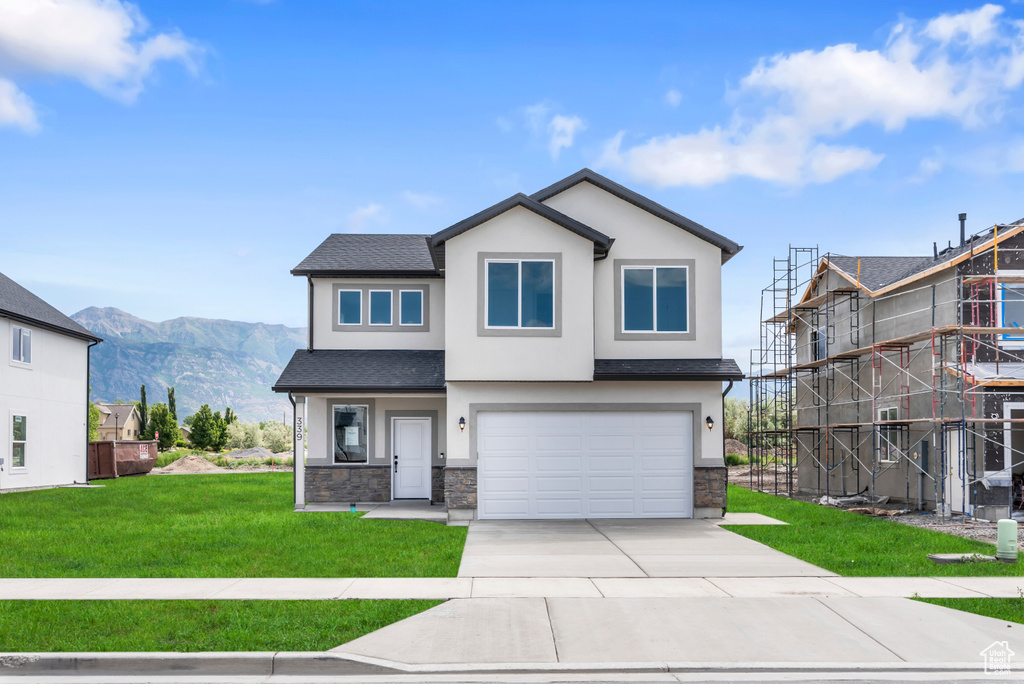 View of front of property featuring stucco siding, stone siding, driveway, and a mountain view