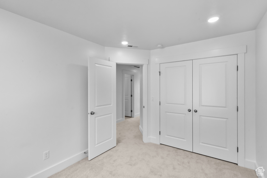 Unfurnished bedroom with light carpet, a closet, and recessed lighting