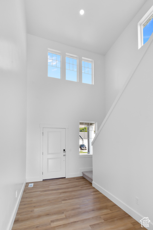 Foyer with a towering ceiling, light wood-style floors, and recessed lighting