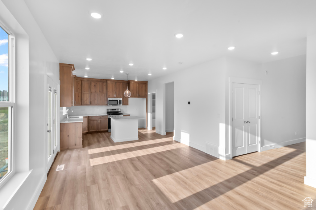 Kitchen with appliances with stainless steel finishes, light countertops, open floor plan, recessed lighting, and light wood-type flooring