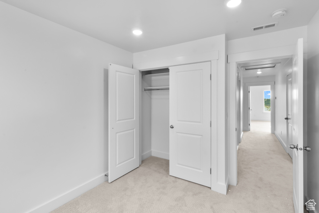 Unfurnished bedroom featuring light colored carpet, a closet, and recessed lighting