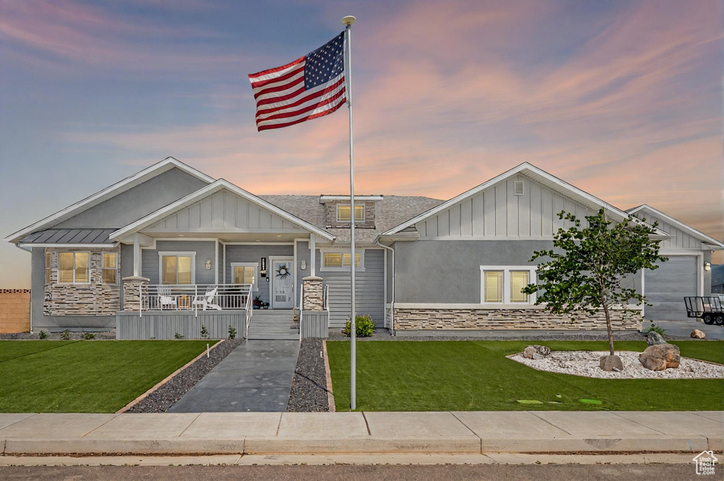 Craftsman-style house featuring board and batten siding, a porch, stone siding, and a lawn