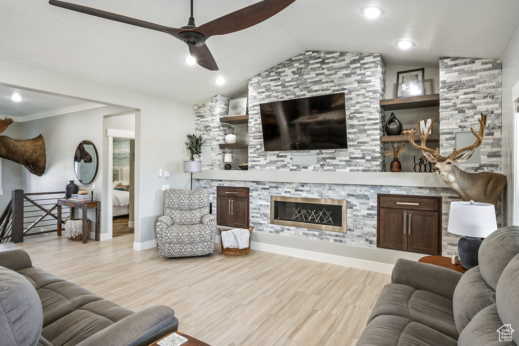 Living area with a fireplace, ceiling fan, vaulted ceiling, and wood finished floors