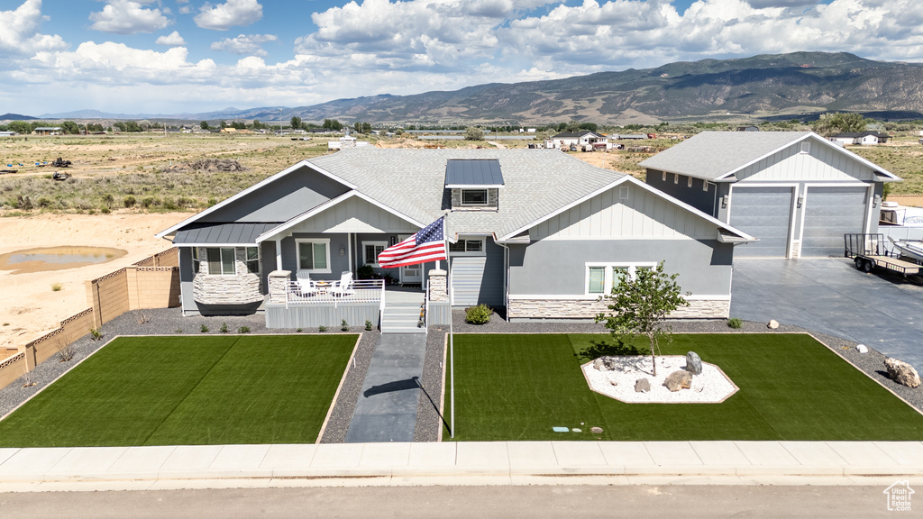 View of front of house with stone siding, a mountain view, and a fenced backyard