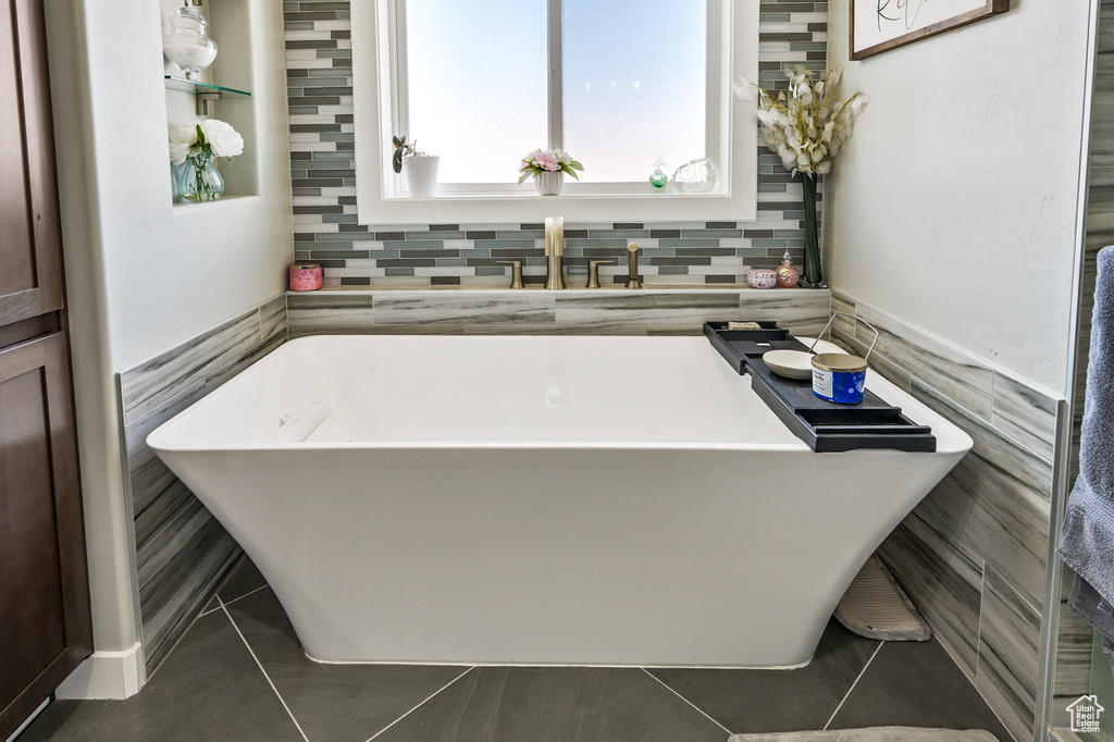 Full bathroom with a soaking tub, tile patterned floors, and tile walls